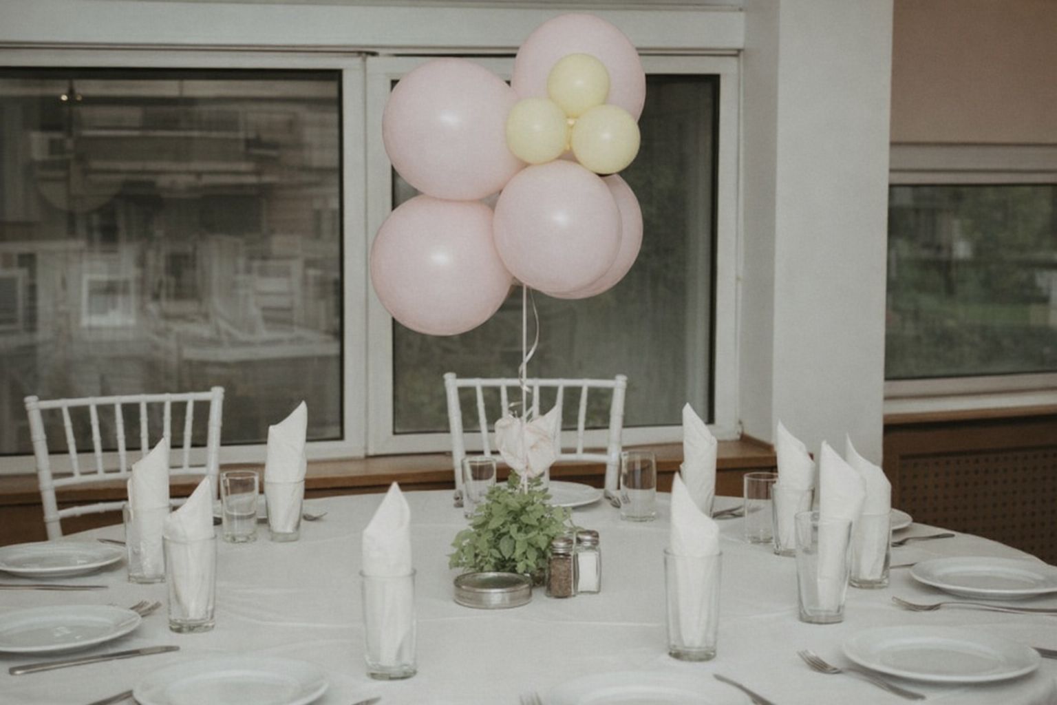 Ett dukat runt bord med ljusrosa och gula ballonger i mitten.